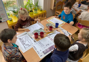 Dzieci malują farbami za pomocą pędzli.